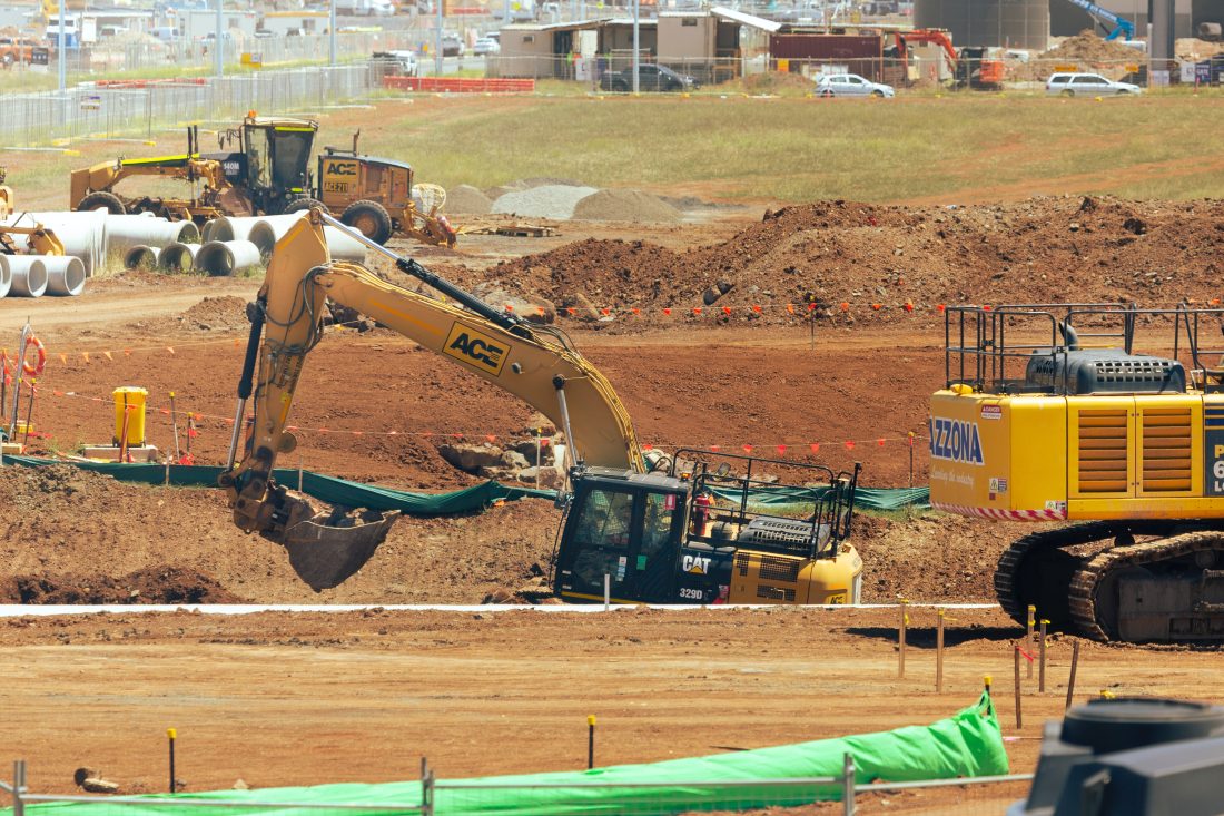 A construction site with a yellow bulldozer and a yellow excavator working on projects.